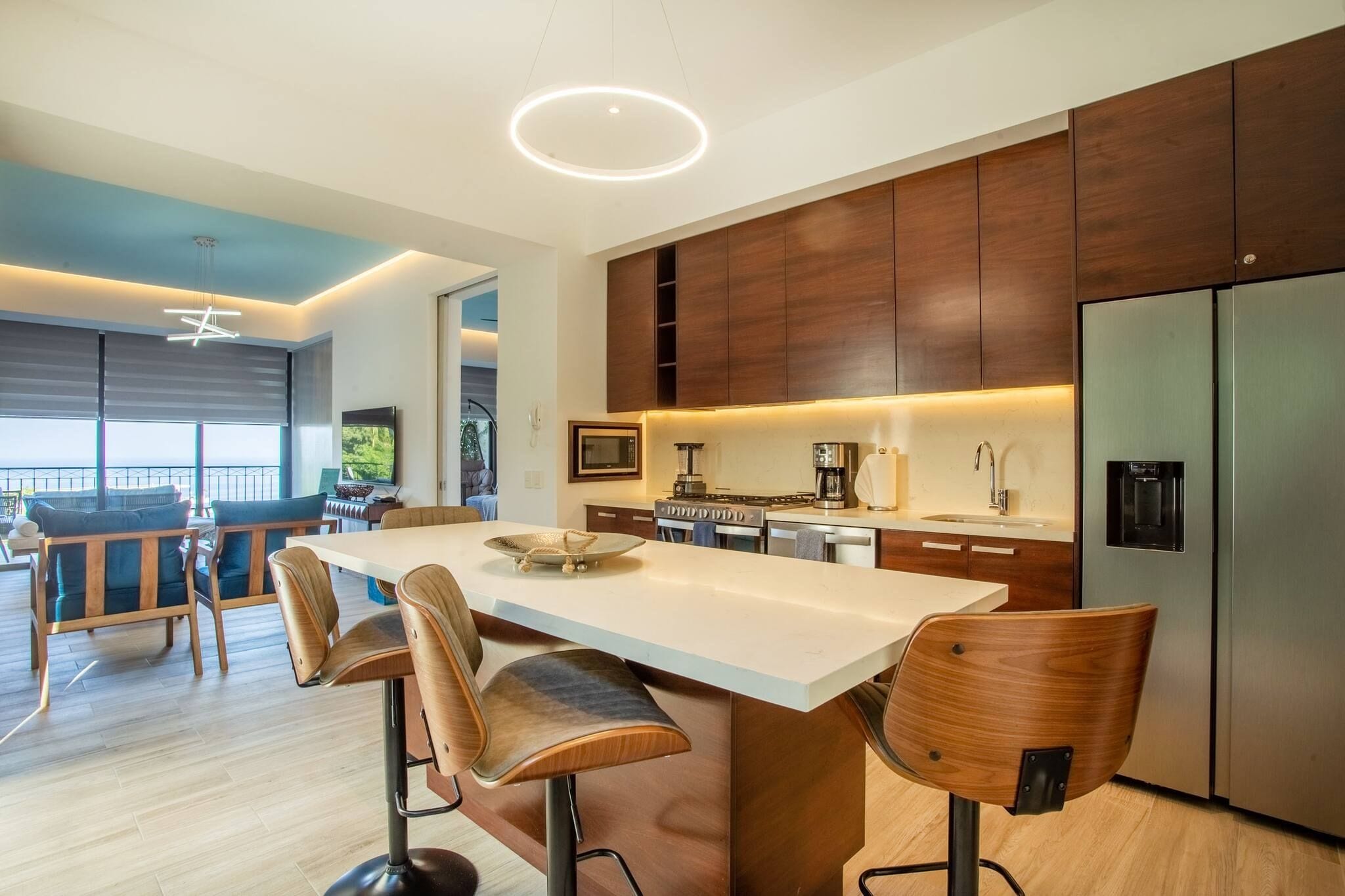 A modern kitchen with a central island, wooden cabinets, and stainless steel appliances.