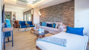 Ein modernes Wohnzimmer mit Sofa, Sesseln, Couchtisch und Bett.