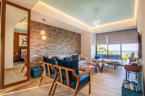 A modern living room with a stone wall, wooden furniture, and large windows.