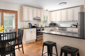 Una cocina moderna con armarios blancos, encimera negra y suelo de madera.