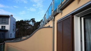 A modern building with a curved facade, large windows, and a brown shuttered door. - Kurparkcarree - Apartment "Meeresbrise" (Ostseebad Juliusruh)