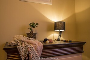 Desk with a potted plant, lamp, and personal items sits against a cream-colored wall.