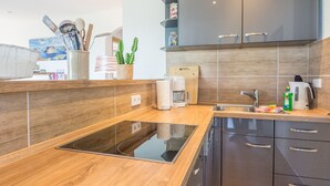 Une cuisine moderne avec un plan de travail en bois, une cuisinière encastrée, des meubles de rangement sombres et un évier.