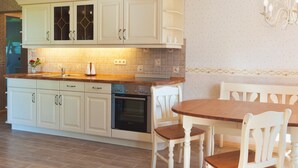 Eine Küche mit weißen Schränken, einer Holz Arbeitsplatte und einem Essbereich mit einem Holztisch und weißen Stühlen.