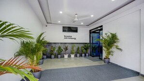 A reception area with a ceiling fan, potted plants, and a sign indicating it's a cafe and restaurant. - Hotel Nevesa Inn (Bengaluru)