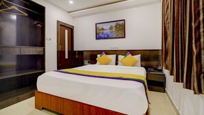 A hotel room with a large bed, a wooden headboard, a painting on the wall, and a curtain on the window. - Hotel Nevesa Inn (Bengaluru)
