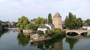 Een historische stadsgezicht met een rivier, bruggen en middeleeuwse torens.