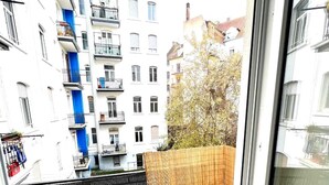 Uitzicht vanaf een balkon met een betegelde vloer, een zwart metalen hek en een houten omheining.