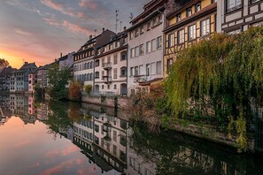 Eine Reihe traditioneller europäischer Häuser entlang eines ruhigen Flusses bei Sonnenuntergang.