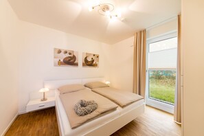 Une chambre à coucher moderne avec un grand lit, des tables de chevet et des œuvres d’art accrochées au mur.