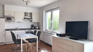 Une cuisine moderne avec des meubles blancs, un four à micro-ondes, une cuisinière et un coin repas comprenant une table et des chaises.