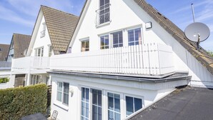 A white two-story house with a sloped roof, a balcony, and a satellite dish. - Ferienwohnung "meeresrauschen" (Breege)