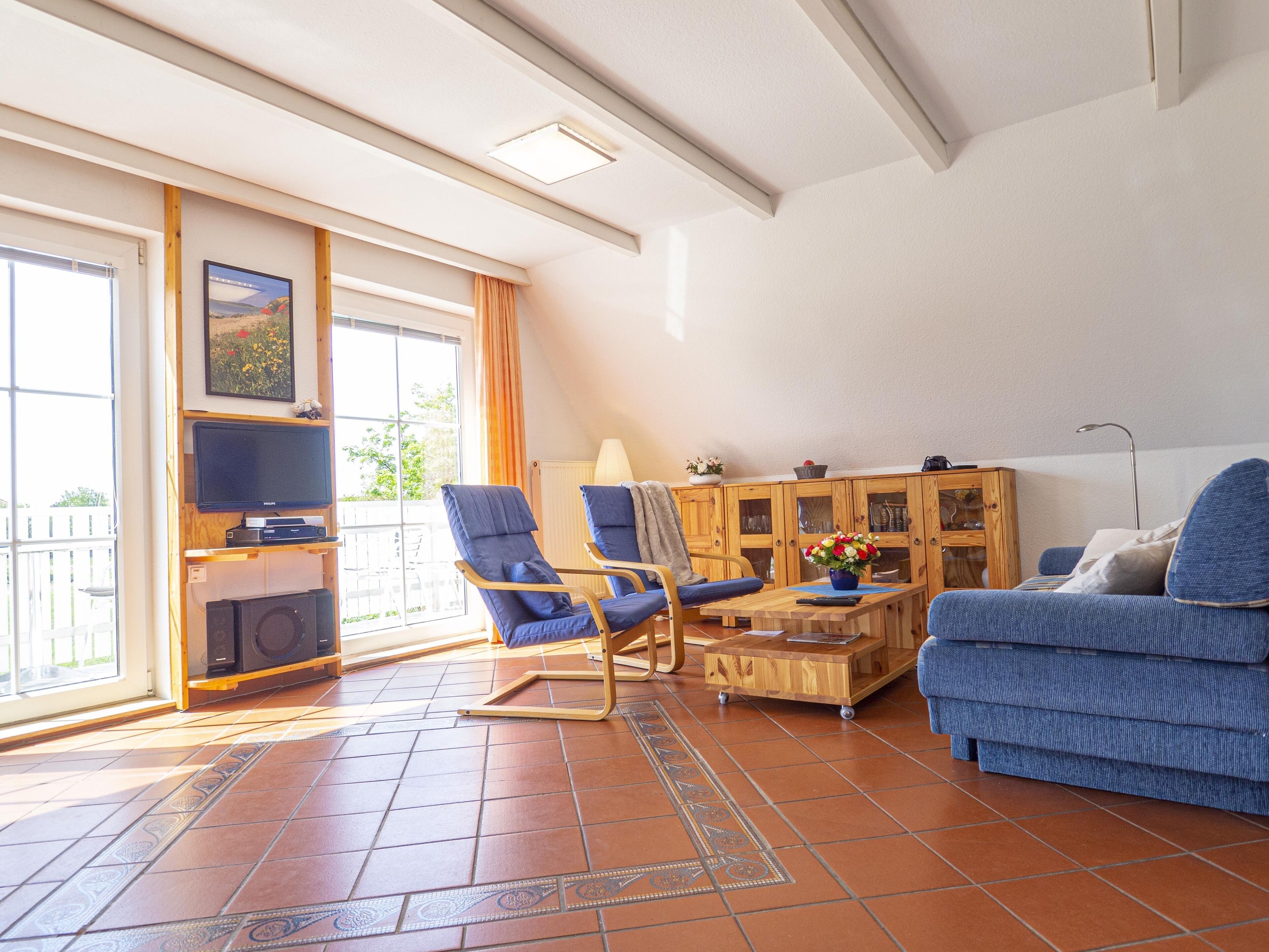 Una sala de estar con un sofá, dos sillones, una mesa de centro, un televisor y un aparador.