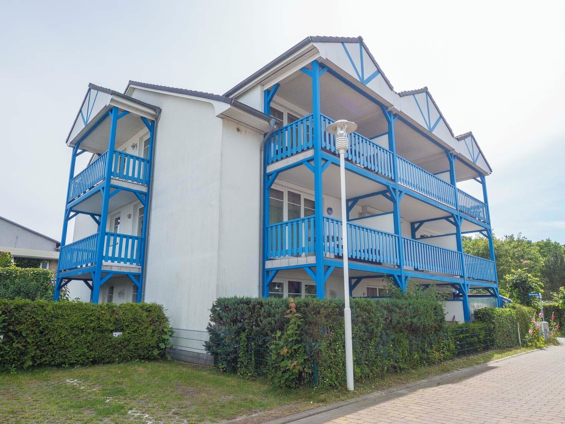 A multi-story building with blue balconies and a white facade.
