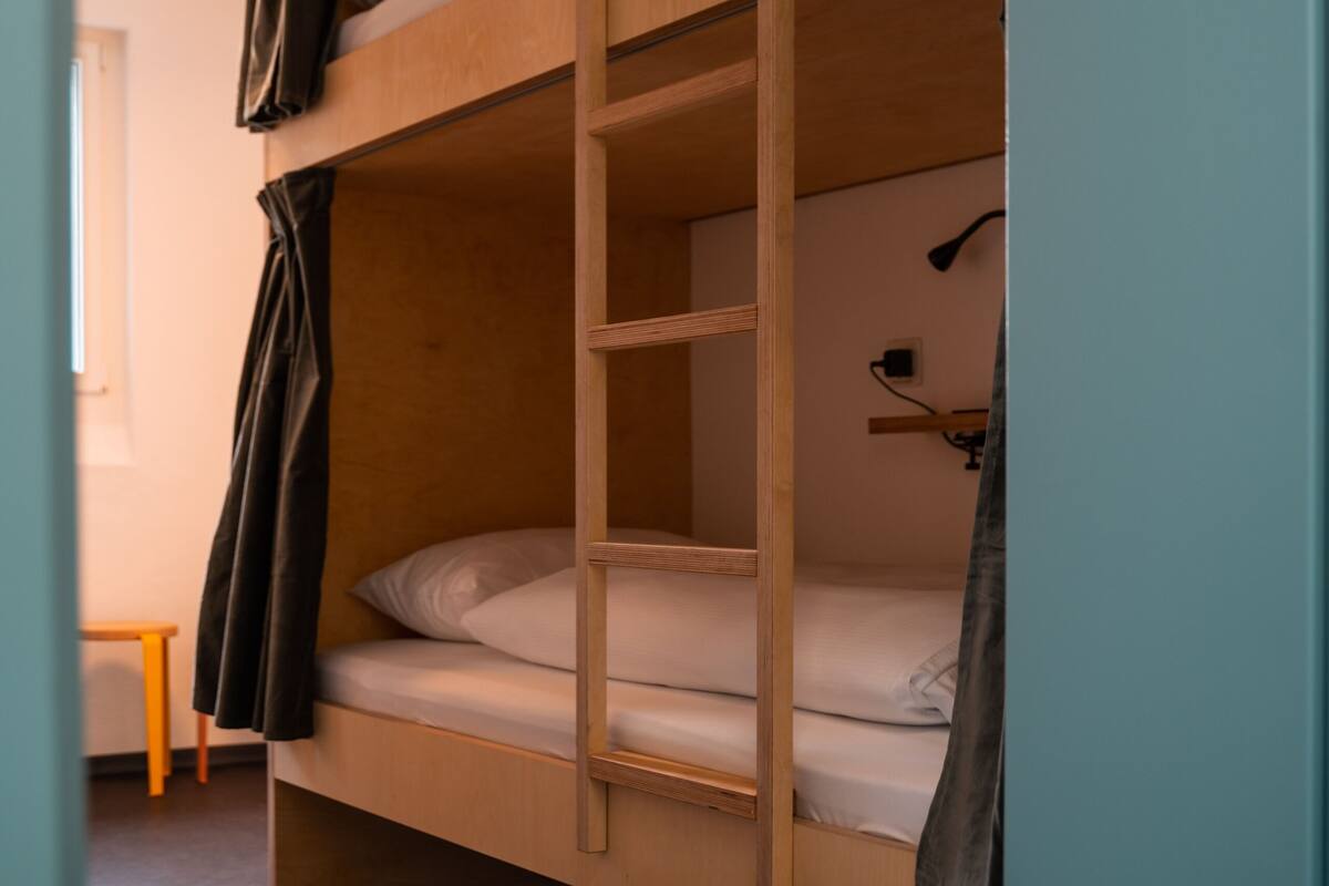 A bunk bed with a ladder, a small table, and a hanging lamp.