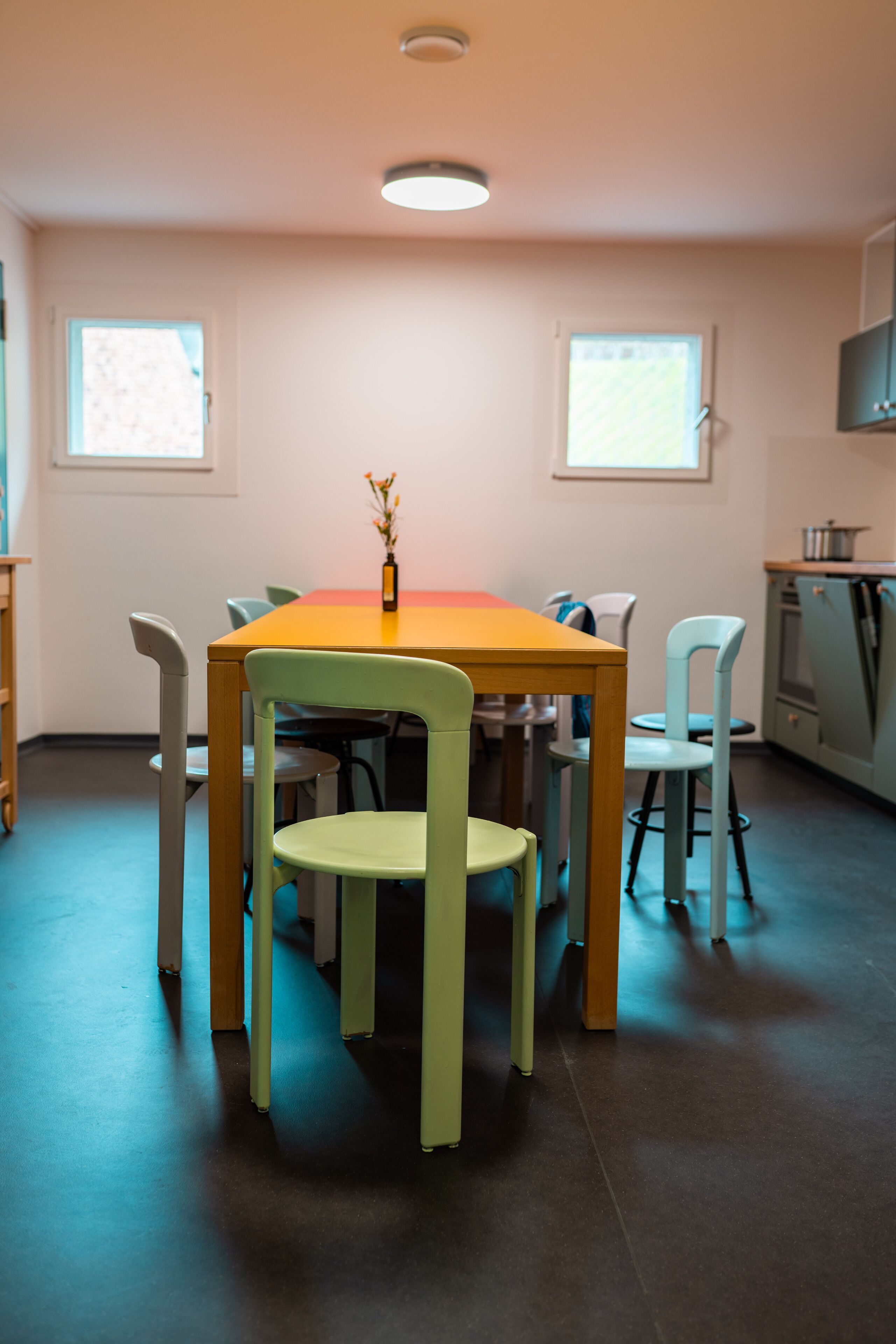 A dining area with a table and chairs, a vase with flowers, and a window.