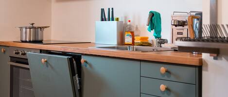 A modern kitchen with grey cabinets, a wooden countertop, and a built-in oven.