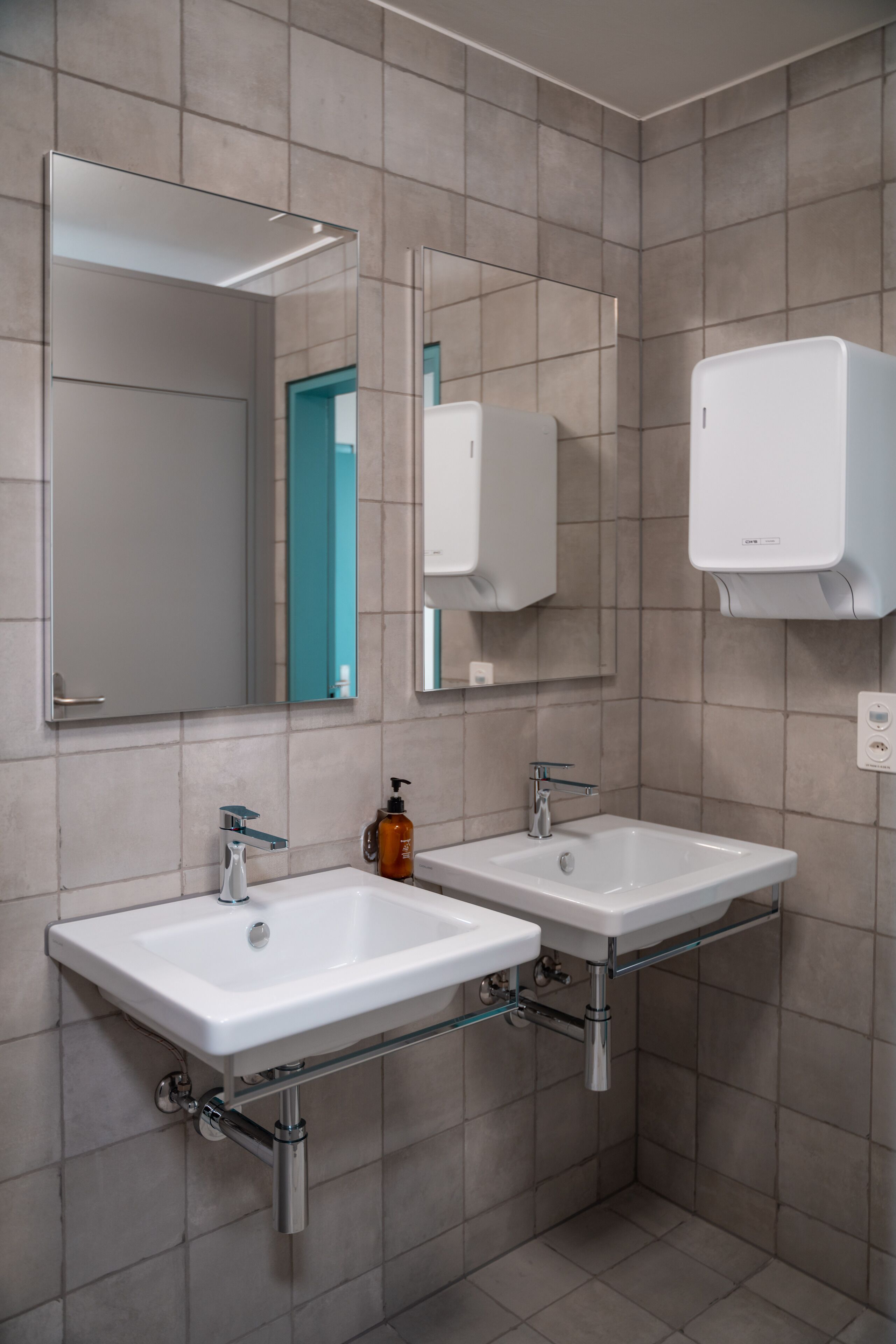 Ein modernes Badezimmer mit zwei Waschbecken, einem großen Spiegel und einer Seifenspender.