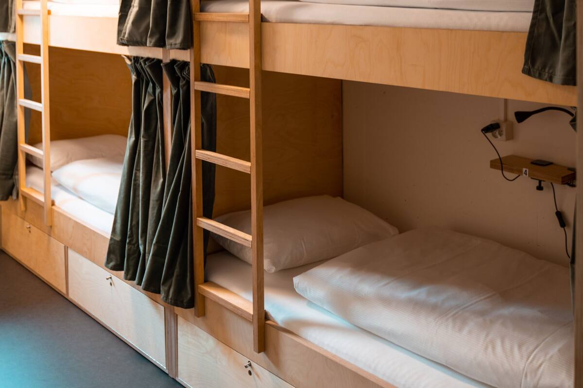 A bunk bed room with a wooden ladder, a desk, and a small shelf.
