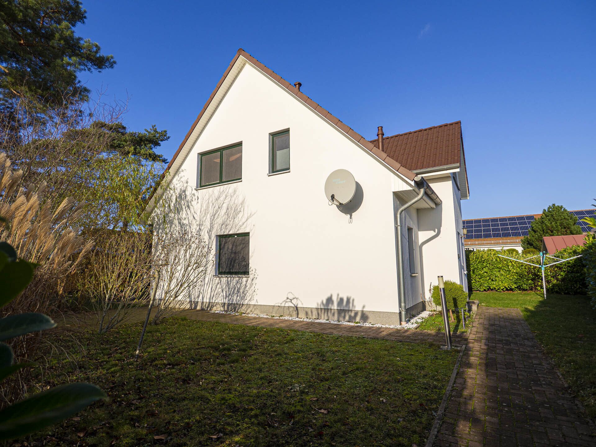 A white two-story house with a brown roof, a satellite dish, and a small satellite dish on the side.