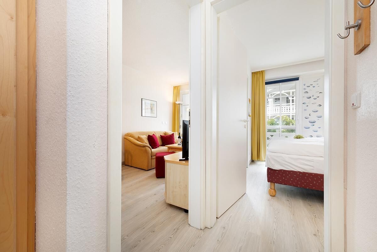Een hotelkamer met een bed, een bureau met stoel, een bank en een raam met gordijnen.