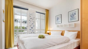 Ein Hotelzimmer mit einem großen Bett, einem Fenster mit gelben Vorhängen und Bildern an der Wand.