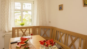 Ein Essbereich mit Holztisch, einem Fenster mit Vorhängen und Blick auf Grünflächen.