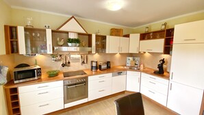 A modern kitchen with white cabinets, a microwave, a coffee maker, and a toaster. - Ferienhaus "sabrina" (Sassnitz)