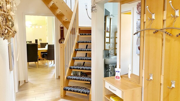 A staircase with black and white patterned steps leading to a room with a wooden desk, a chair, and a shelf with a book. - Ferienhaus "sabrina" (Sassnitz)