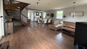 A spacious living area with a wooden staircase, a dining table, and a sofa. - Ferienhaus "sarcander" (Glowe)