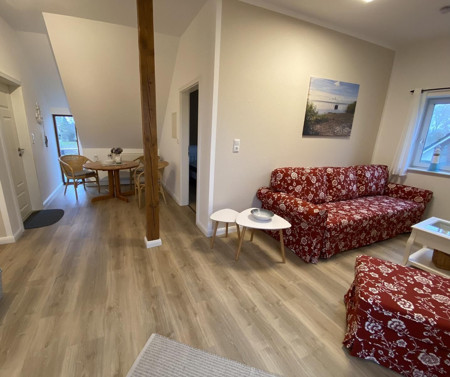 Un salón acogedor con un sofá floral, una mesita redonda y una mesa de comedor con sillas.