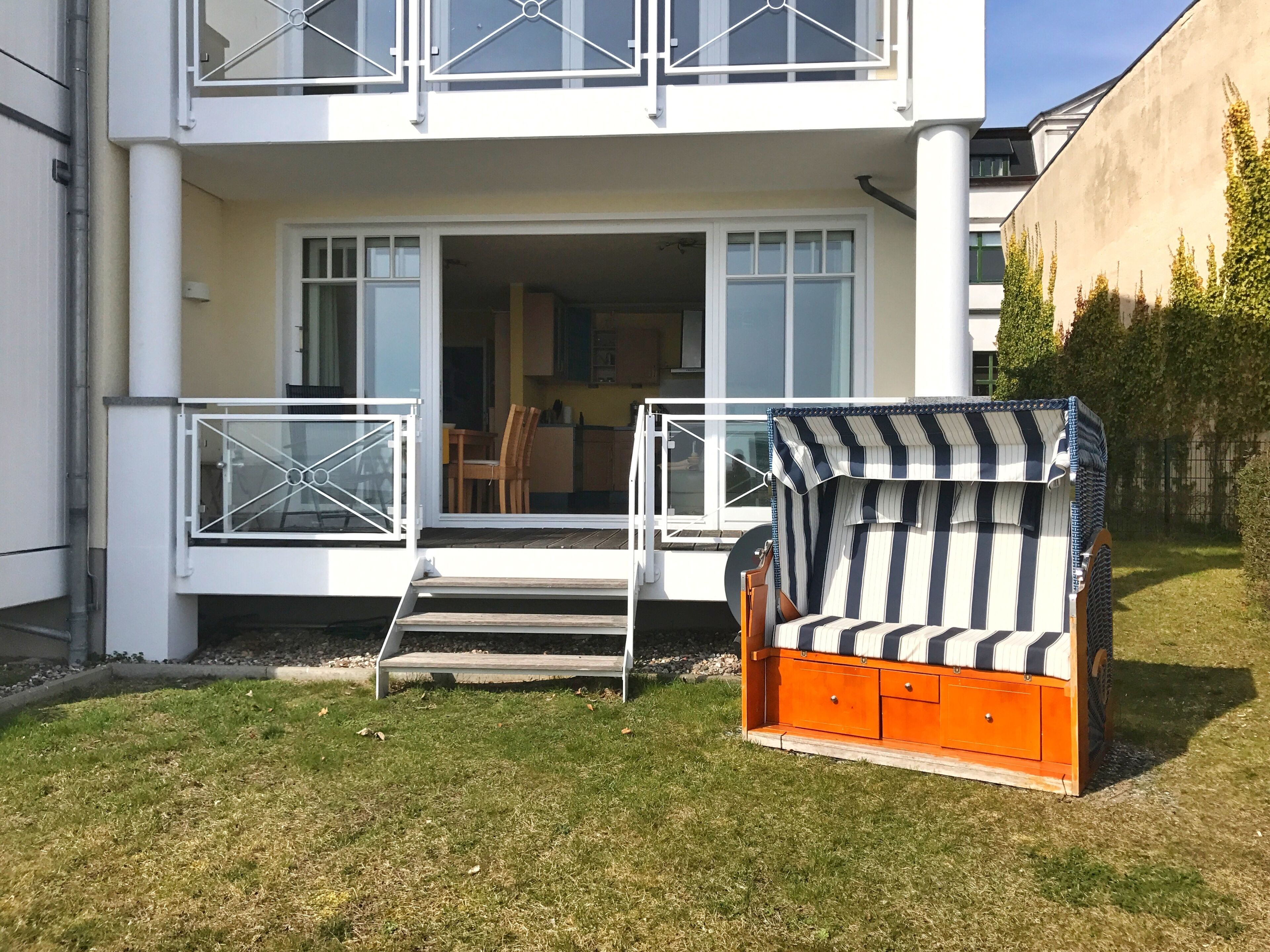 Ein zweistöckiges Gebäude mit Balkon, einem Holzstuhl und einem kleinen Tisch.