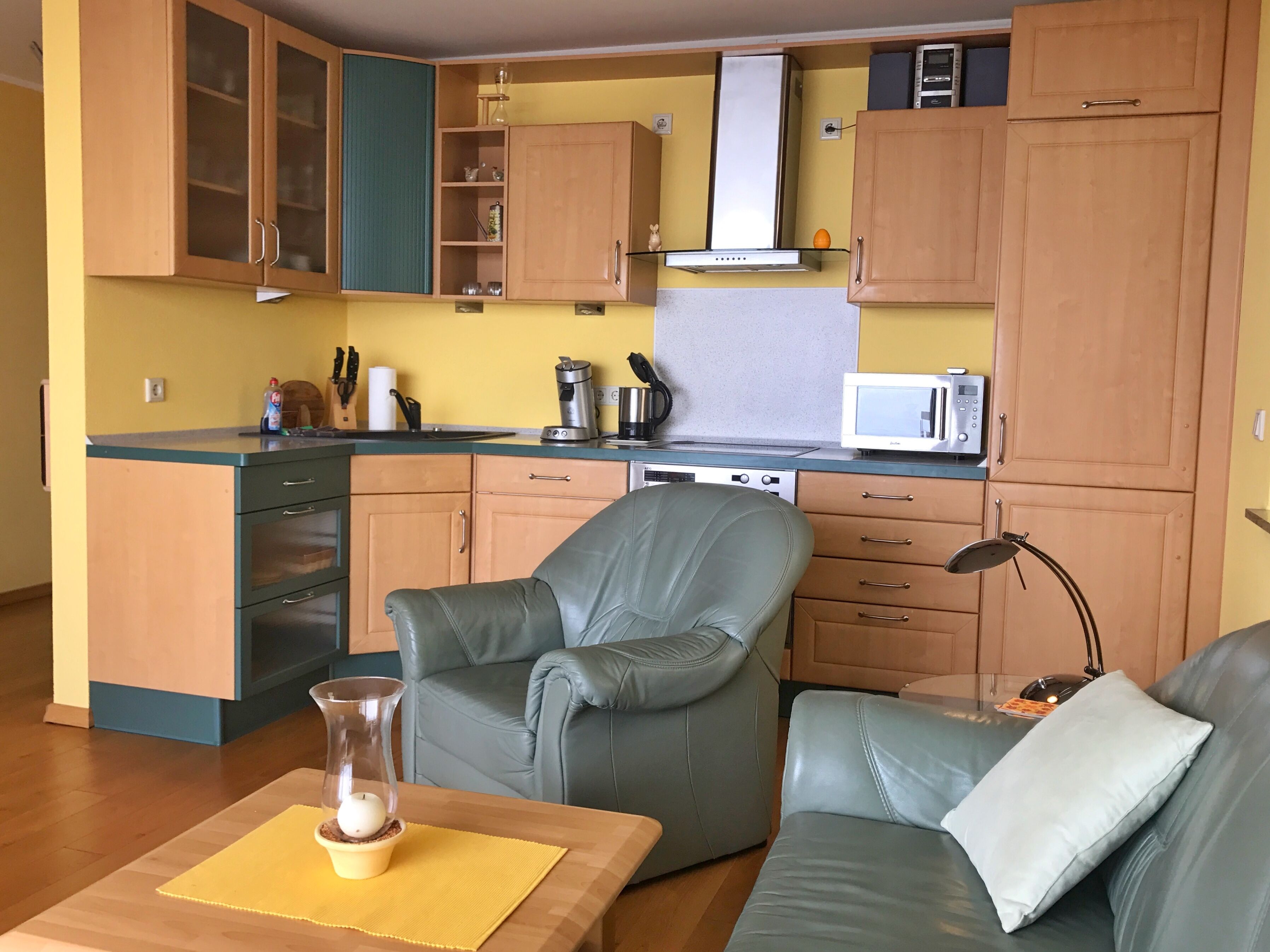 Un espai habitable compacte amb cuina americana, zona de dinar amb taula i zona de seients amb sofà.