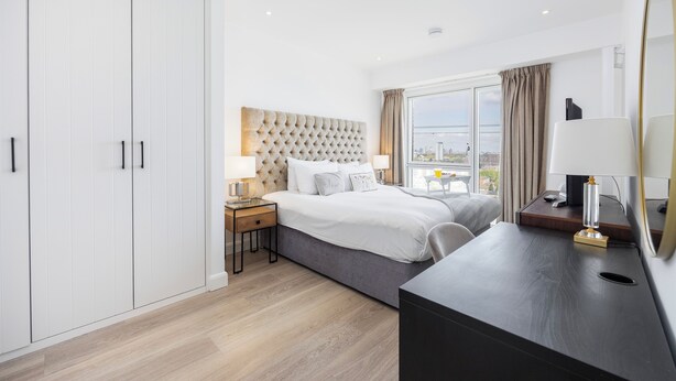 Habitación de hotel con una cama grande, un escritorio, un armario y vistas a la ciudad.