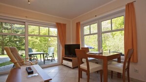 Ein Zimmer mit Esstisch, Stühlen, Fernseher und einer Couch.