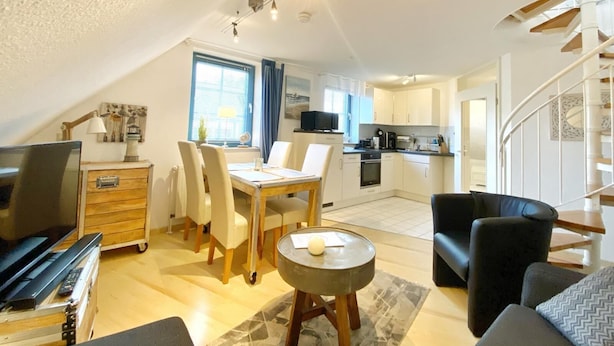 Un espacio habitable compacto con comedor, cocina y escalera.