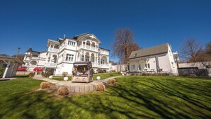 A large white building with multiple balconies and a well-maintained lawn.