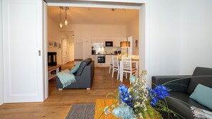 An open-plan living area with a sofa, dining table, and kitchen in the background.