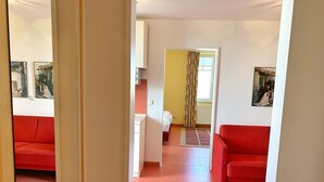Ein Zimmer mit roten Sofas, einer Küchenzeile und einem Flur, der in ein weiteres Zimmer führt.