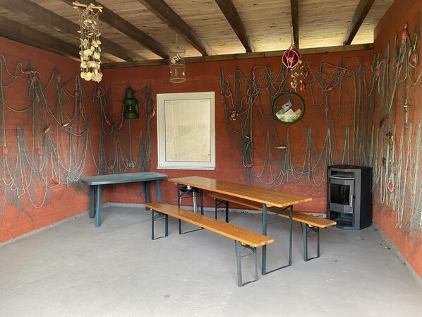 A rustic room with a wooden table and benches, a television, and fishing nets on the walls.