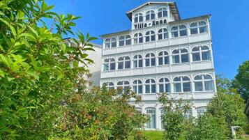 Ein mehrstöckiges Gebäude im klassischen Stil, mit Rundbogenfenstern und einem markanten Balkon im oberen Geschoss.