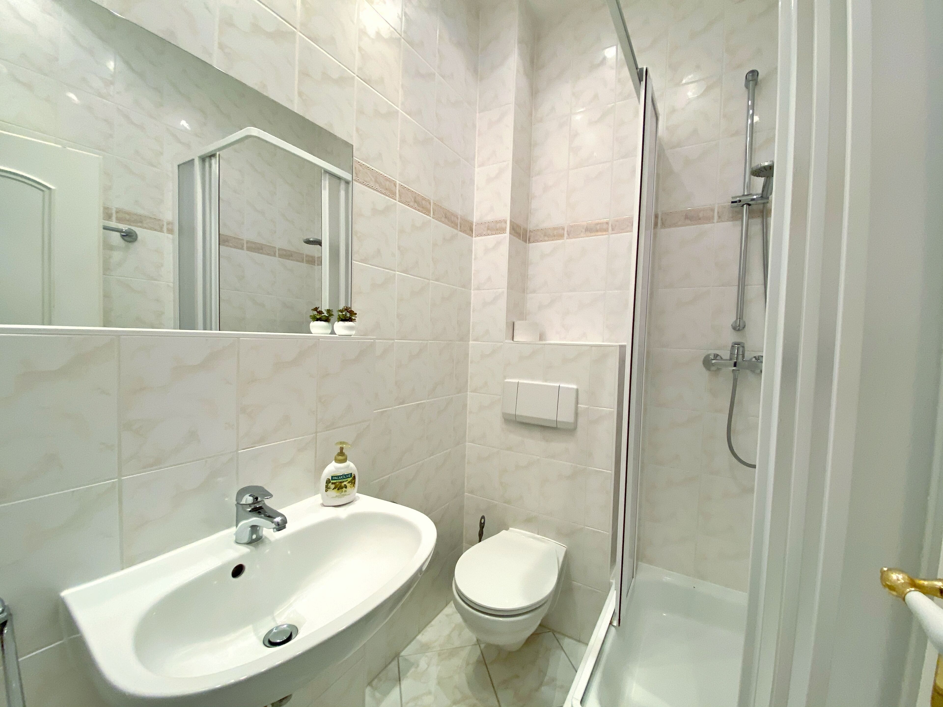 A modern bathroom with a sink, toilet, and glass-enclosed shower.