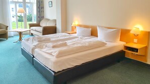 A hotel room with a large bed, two bedside tables with lamps, a sofa, and a chair. - Ferienappartement 10 in der Villa Anna in Sassnitz (Sassnitz)