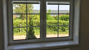 Una ventana con vistas a un jardín y una masa de agua.