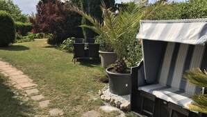 Un jardín con un patio, una banca para sentarse y plantas en macetas.