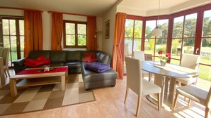 A living room with a sofa, a coffee table, and a dining area with a table and chairs.
