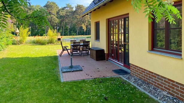 A patio with outdoor furniture, a grill, and a view of a lake.