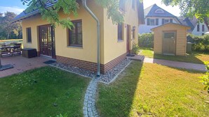 A two-story house with a brick foundation, a small attached garage, and a well-maintained lawn.