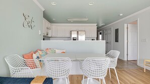 Una sala de estar moderna con sillas de estructura metálica blanca, un sofá y una mesa de comedor.
