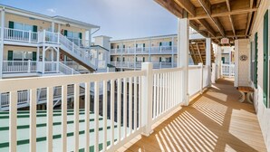 Un hotel frente a la playa con varios balcones, terraza de madera y un paseo cubierto.